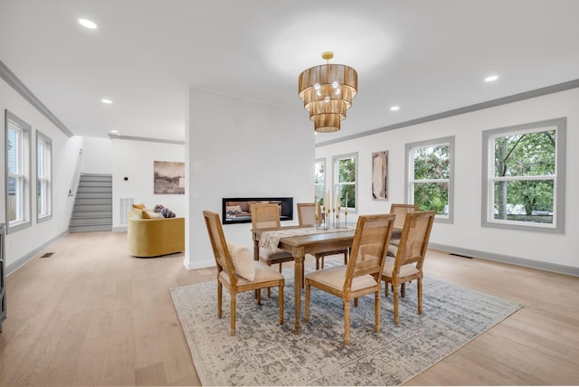 dining room with light hardwood / wood-style flooring, crown molding, and a chandelier