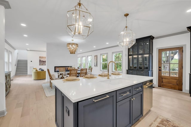 kitchen with decorative light fixtures, plenty of natural light, a kitchen island with sink, and sink