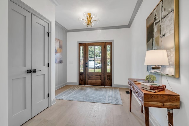 entryway with light hardwood / wood-style floors, crown molding, and a chandelier