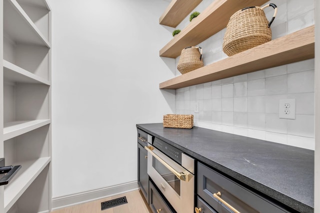 kitchen featuring backsplash, light hardwood / wood-style flooring, and oven