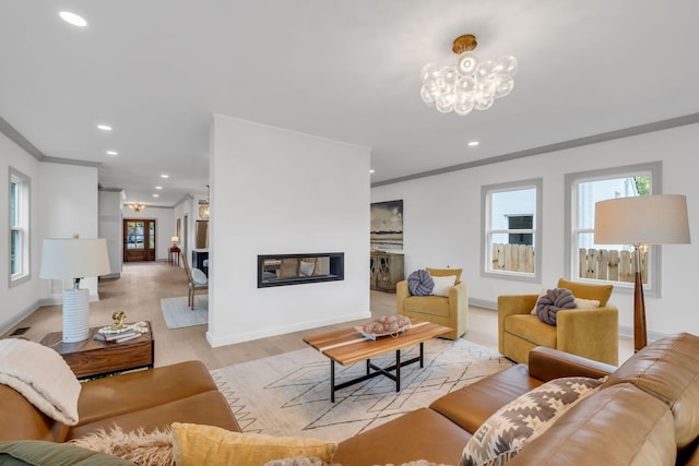 living room with light wood-type flooring, ornamental molding, and a chandelier