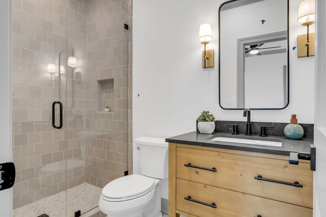 bathroom with ceiling fan, vanity, a shower with shower door, and toilet