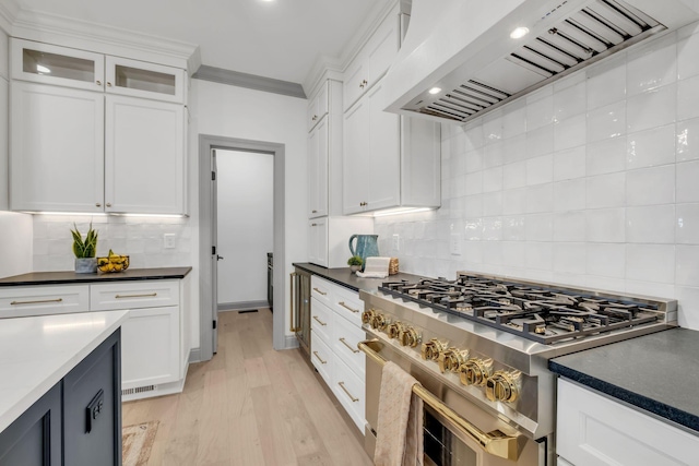 kitchen featuring white cabinets, custom exhaust hood, range with two ovens, and decorative backsplash