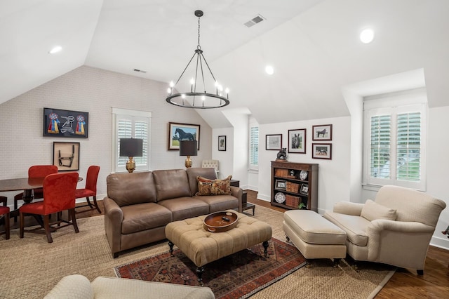 living room featuring wood-type flooring, an inviting chandelier, vaulted ceiling, and brick wall