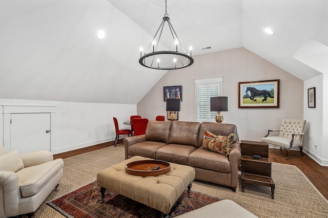 living room featuring wood-type flooring, vaulted ceiling, a notable chandelier, and brick wall