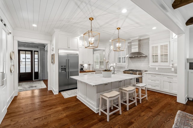 kitchen featuring white cabinetry, wall chimney exhaust hood, high quality appliances, and a kitchen island with sink