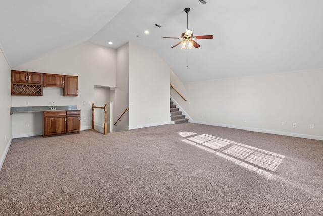 unfurnished living room with ceiling fan, high vaulted ceiling, light colored carpet, and indoor wet bar