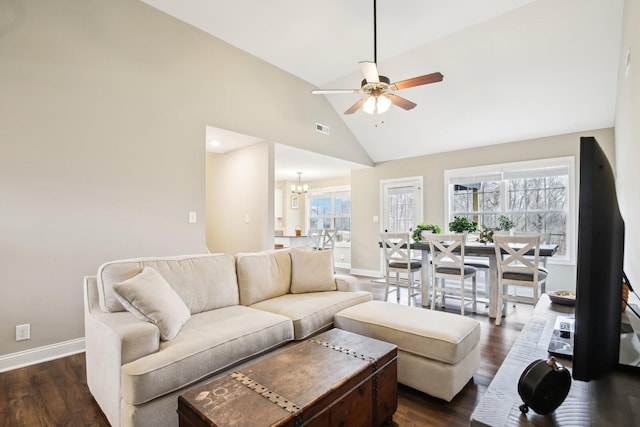 living room with ceiling fan with notable chandelier, dark hardwood / wood-style floors, and high vaulted ceiling