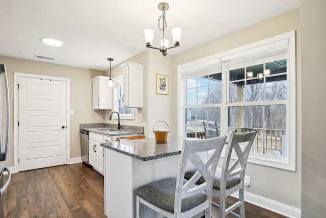 kitchen featuring stainless steel dishwasher, sink, a notable chandelier, white cabinetry, and hanging light fixtures