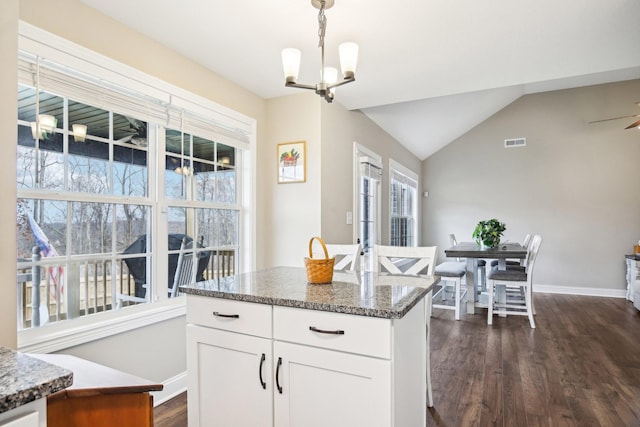 kitchen featuring white cabinets, a center island, dark stone counters, and pendant lighting