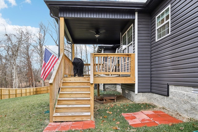 entrance to property with a yard, ceiling fan, and a wooden deck