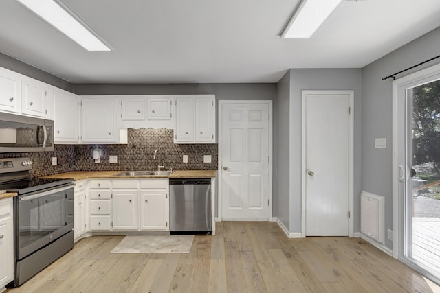 kitchen with white cabinets, sink, stainless steel appliances, and tasteful backsplash