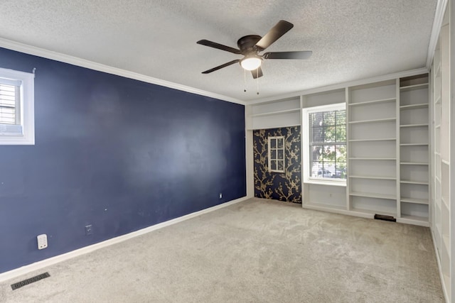 unfurnished room featuring ornamental molding, a textured ceiling, light colored carpet, and a healthy amount of sunlight