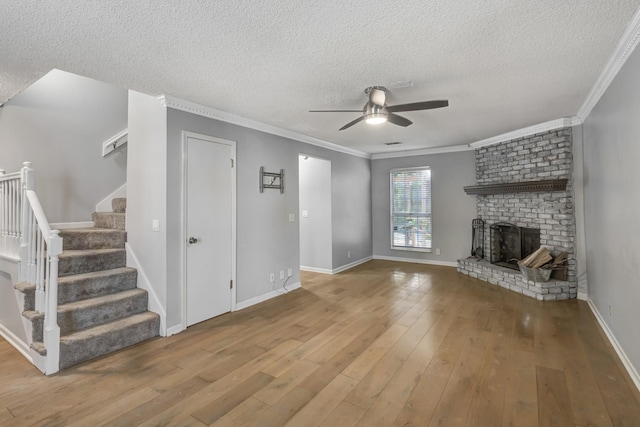 unfurnished living room featuring ceiling fan, hardwood / wood-style floors, a textured ceiling, a fireplace, and ornamental molding