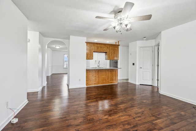 unfurnished living room with ceiling fan, sink, and dark hardwood / wood-style floors