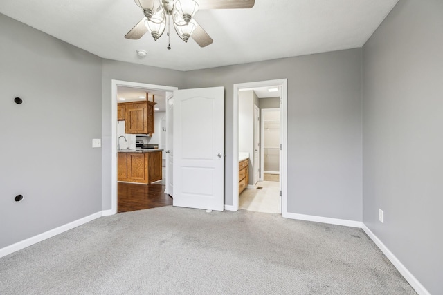 unfurnished bedroom with ceiling fan, light carpet, and ensuite bath