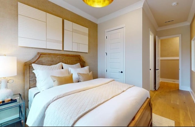 bedroom with crown molding and light wood-type flooring