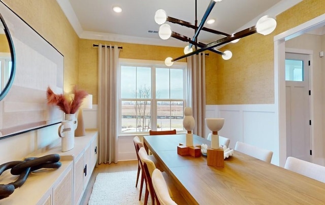 dining space featuring light wood-type flooring, crown molding, and a notable chandelier