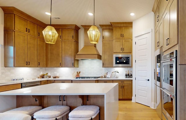 kitchen with decorative light fixtures, decorative backsplash, stainless steel appliances, and custom exhaust hood