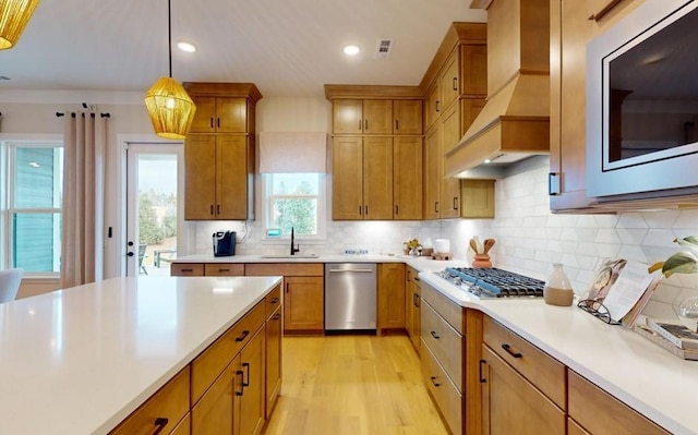 kitchen featuring custom exhaust hood, backsplash, pendant lighting, and sink