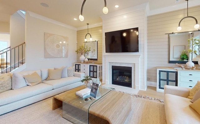 living room with wood walls, crown molding, and light wood-type flooring