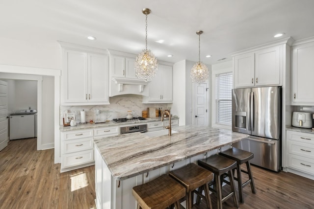 kitchen with dark wood finished floors, a sink, stainless steel appliances, a kitchen breakfast bar, and backsplash