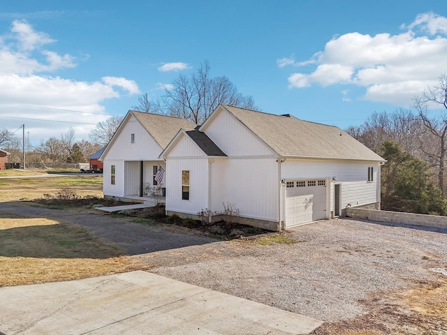 view of front of house with an attached garage, a shingled roof, and gravel driveway