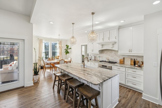 kitchen with tasteful backsplash, light stone counters, dark wood-style floors, a notable chandelier, and stainless steel appliances