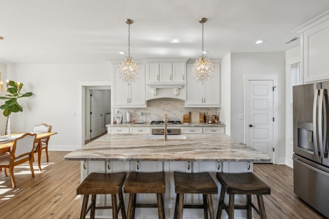 kitchen with decorative backsplash, a kitchen breakfast bar, appliances with stainless steel finishes, and an inviting chandelier