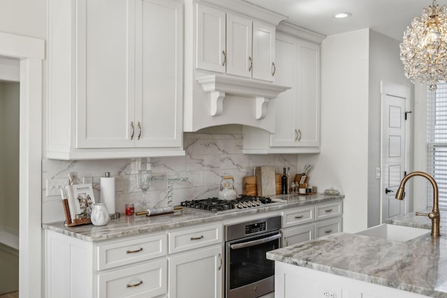 kitchen with a sink, decorative backsplash, stainless steel appliances, white cabinets, and under cabinet range hood