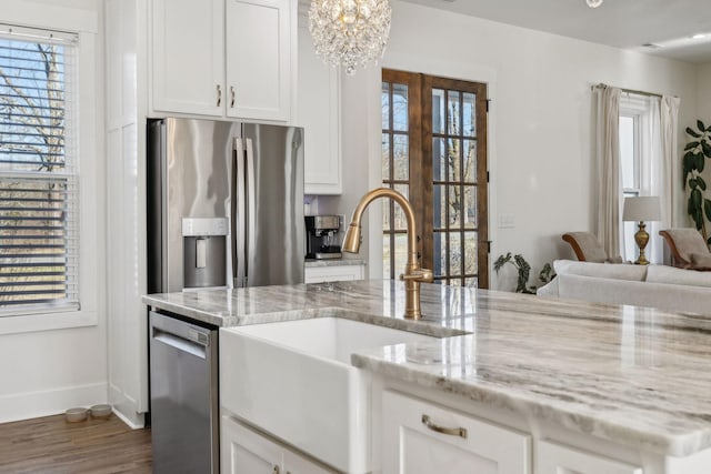 kitchen featuring dark wood-type flooring, light stone countertops, appliances with stainless steel finishes, white cabinetry, and a sink