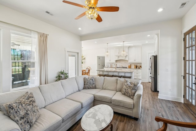 living area featuring recessed lighting, dark wood-style floors, visible vents, and baseboards