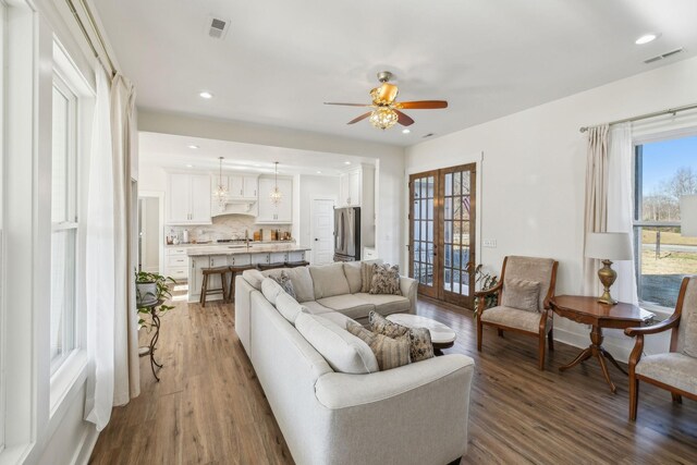 living room with visible vents, light wood-style flooring, french doors, and a ceiling fan