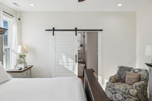 bedroom featuring a barn door, recessed lighting, and visible vents