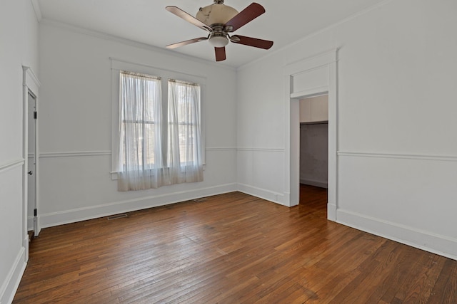 empty room with ceiling fan, ornamental molding, and dark wood-type flooring