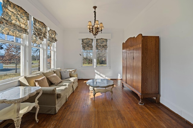 living area featuring a chandelier, crown molding, a wealth of natural light, and dark wood-type flooring