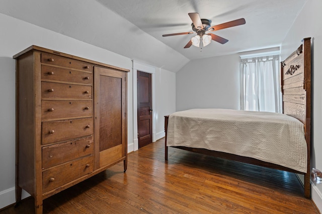 bedroom with dark hardwood / wood-style flooring, vaulted ceiling, and ceiling fan