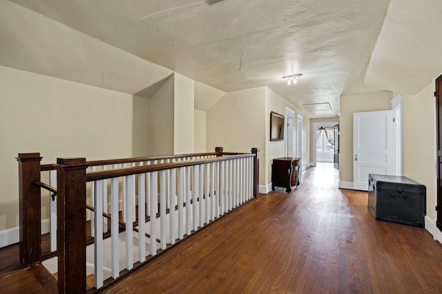 corridor with a textured ceiling, vaulted ceiling, and hardwood / wood-style flooring