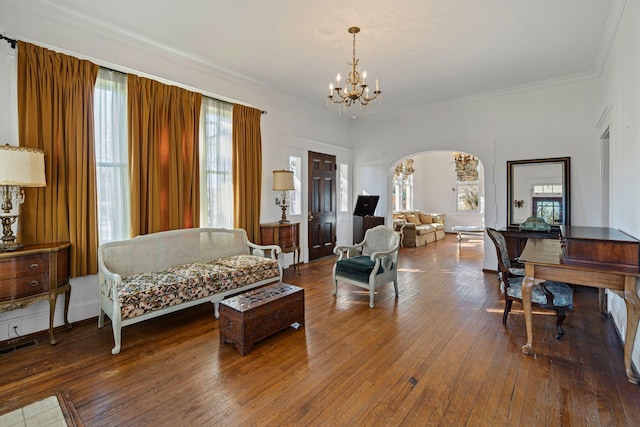 living room featuring hardwood / wood-style flooring, an inviting chandelier, and crown molding