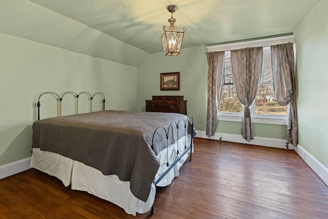 bedroom featuring dark hardwood / wood-style flooring, lofted ceiling, and an inviting chandelier