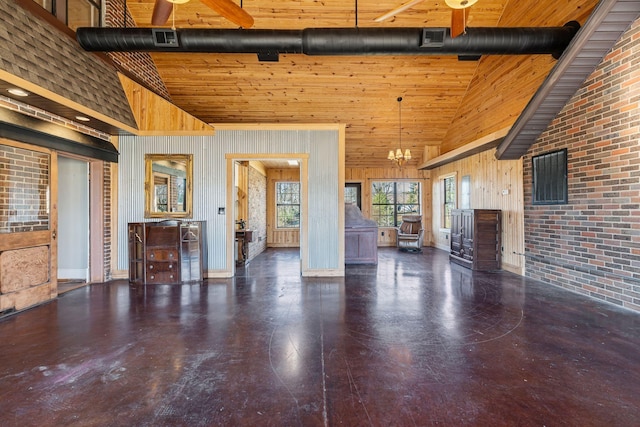 unfurnished living room featuring wood walls, high vaulted ceiling, and a notable chandelier