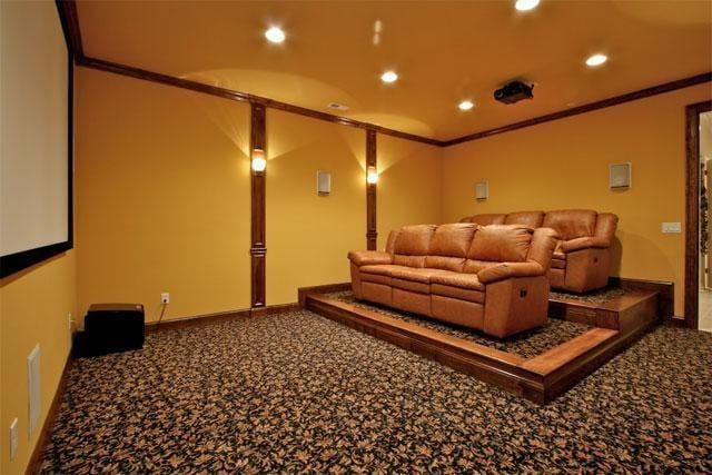 cinema room with ornamental molding and carpet floors