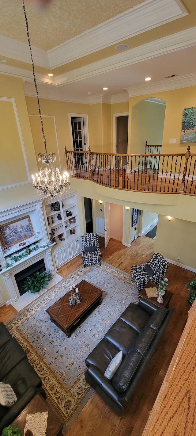 living room with a high end fireplace, wood-type flooring, and ornamental molding