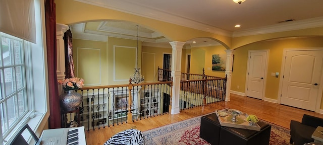 hall featuring hardwood / wood-style floors, ornamental molding, and ornate columns