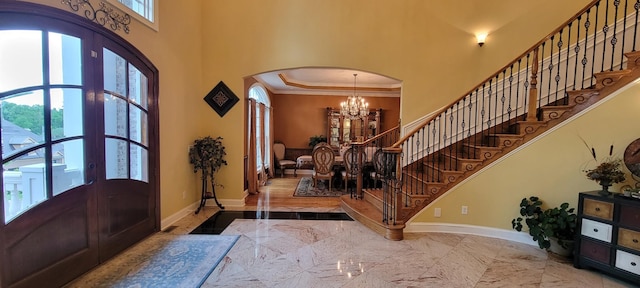 foyer entrance featuring french doors, an inviting chandelier, ornamental molding, and a healthy amount of sunlight