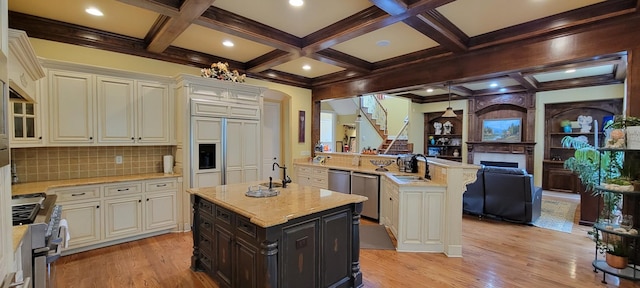 kitchen with decorative backsplash, high quality appliances, light wood-type flooring, and a center island