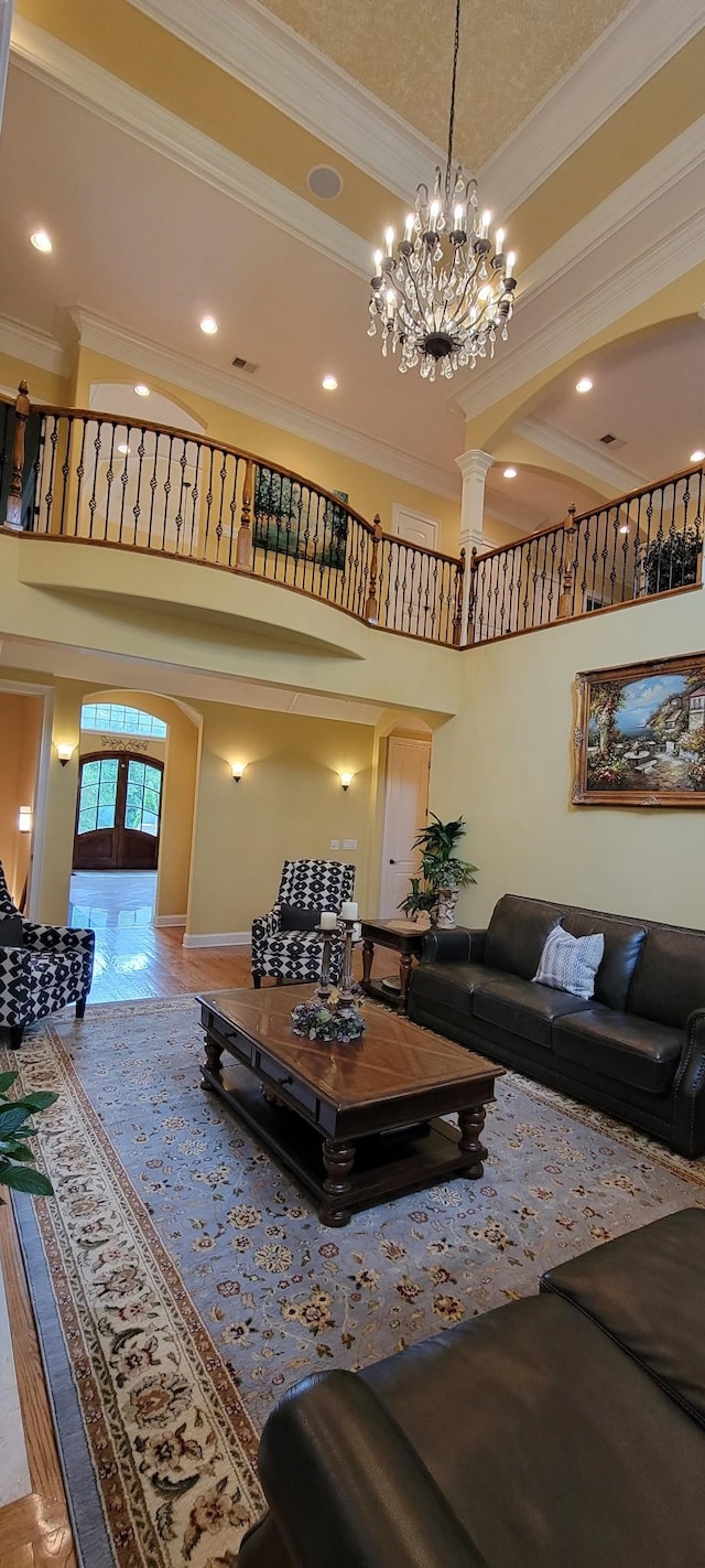 living room featuring a high ceiling, french doors, crown molding, and a chandelier