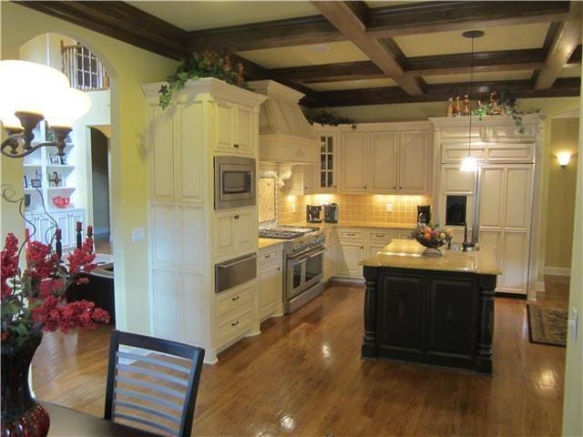 kitchen featuring appliances with stainless steel finishes, a notable chandelier, a kitchen island with sink, and premium range hood