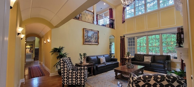 living room featuring a towering ceiling, a chandelier, and hardwood / wood-style floors