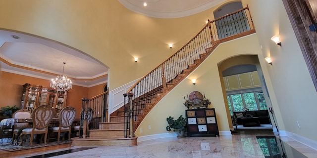 stairs featuring a high ceiling, a chandelier, and ornamental molding